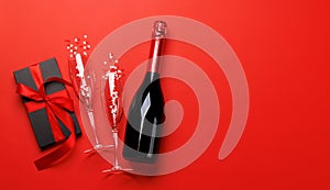 Champagne and gift: Celebratory duo on a red background with text space