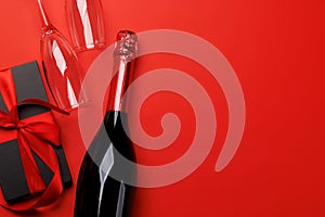 Champagne and gift: Celebratory duo on a red background with text space