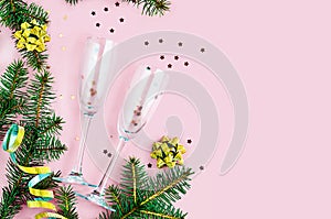 Champagne glass with sparkles and confetti on pink background with fir branches