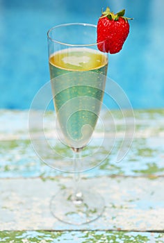 Champagne glass with strawberry on turquiose background