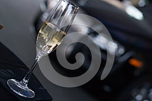 Champagne glass on table with high end car in background