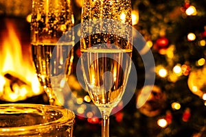 Champagne glasses on the background of Christmas tree and fireplace. New year celebration. Champagne glass close up.