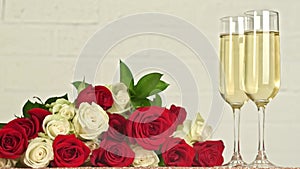 Champagne glasses and bouquet of red, white roses on white background