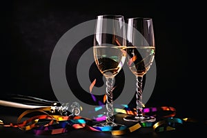 Champagne glasses and colourful streamers and glitter confetti on a happy new year background created with generative AI