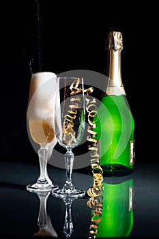 Champagne glasses and green champagne bottle lighted with grid and sidelight.