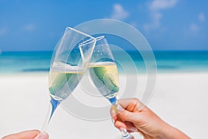 Champagne glasses in hands on beach background. Romantic honeymoon background