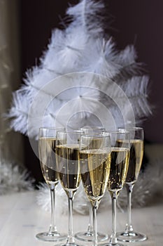 Champagne glasses and a New Year`s entourage with a Christmas tree, snowflakes are depicted