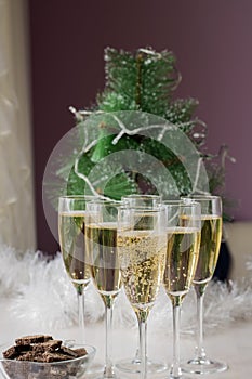 Champagne glasses and a New Year`s entourage with a Christmas tree, snowflakes are depicted