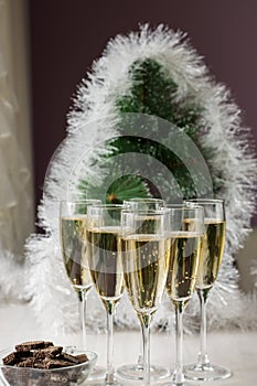 Champagne glasses and a New Year`s entourage with a Christmas tree, snowflakes are depicted