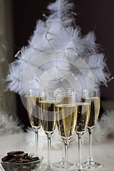 Champagne glasses and a New Year`s entourage with a Christmas tree, snowflakes are depicted