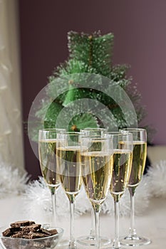 Champagne glasses and a New Year`s entourage with a Christmas tree, snowflakes are depicted