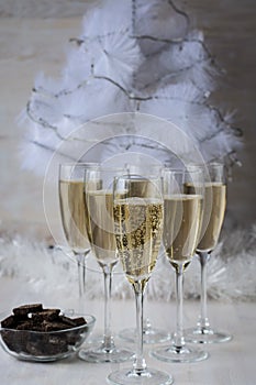 Champagne glasses and a New Year`s entourage with a Christmas tree, snowflakes are depicted