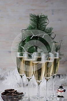 Champagne glasses and a New Year`s entourage with a Christmas tree, snowflakes are depicted