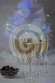 Champagne glasses and a New Year`s entourage with a Christmas tree, snowflakes are depicted