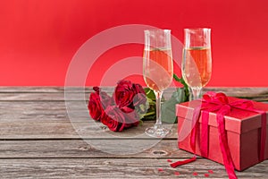 Champagne glasses, red gift box and red roses