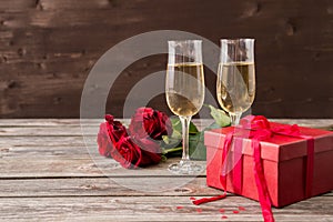 Champagne glasses, red gift box and red roses