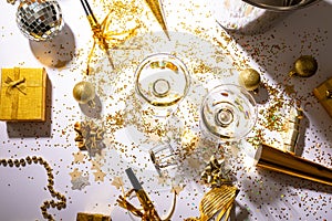 Champagne glasses on scattered confetti with gift and decoration on table