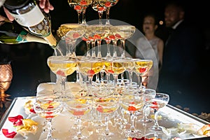 Champagne glasses standing in a tower at the wedding party. Champagne glass pyramid. Pyramid of glasses of wine, champagne, tower