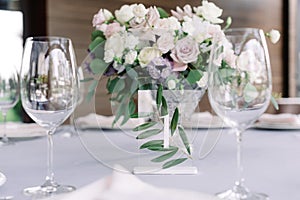 Champagne glasses, table number with number one and beautiful wedding flowers decorate the table at the wedding banquet