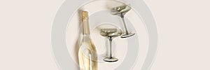 Champagne glasses tinted grey glass, Champagne or sparkling wine bottle on beige background. Festive drink concept