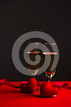 Champagne in glasses of two in romantic valentine concept with heart shaped fabric on red and black background