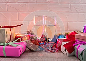 Champagne in glasses on wooden table with colorful Christmas presents