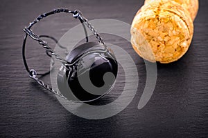 Champagne muselet with black cap and cork on black stone background