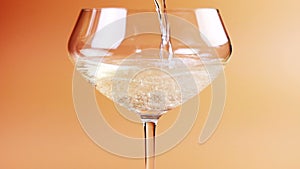 Champagne is poured into a glass on a cream background