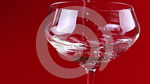 Champagne is poured into a glass on a red background