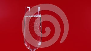 Champagne is poured into a glass on a red background