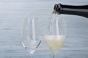 Champagne is pouring from a bottle into a glass, closeup view
