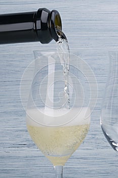 Champagne pouring from a bottle into a glass, front view close-up