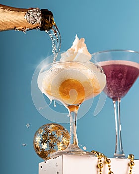 Champagne pouring in two glasses on blue background. Festive champagne and cotton candy cocktails, cheers concept