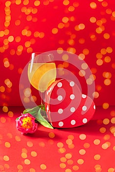 Champagne, present and flower on red background