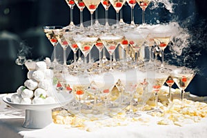 Champagne pyramid on event, party or banquet. cherry in the glass. Dry ice floats