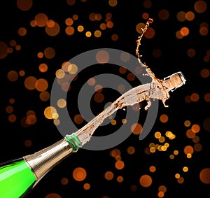 Champagne splashing out of bottle on background