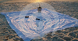 Champagne and sunglasses on the beach at sunset