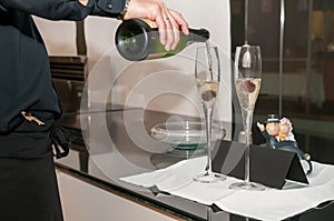 Champagne in two glass glasses with sour cherries that is being served by a waiter.