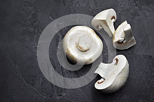 Champignon mushrooms on dark slate background. Vegan food preparation. Top view, copy space