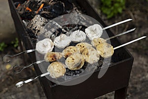 Champignon mushrooms are fried on skewers on the grill. Picnic in nature. Close-up