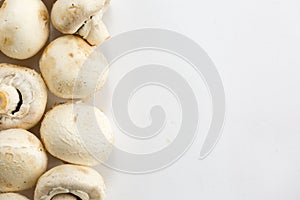 Champignon mushrooms lie vertically on the left on a white background. The concept of minimalism in the kitchen. Place for text.