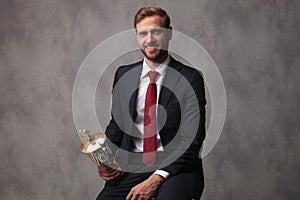 Champion businessman holding his trophy cup and sits