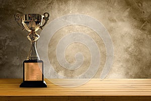 Champion golden trophy placed on wooden table with concrete background. copy space