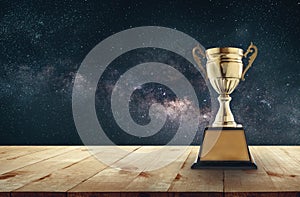 champion golden trophy on wood table with Milky Way background c