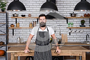 He is a champion in the kitchen. Hipster in kitchen. Mature male. Bearded man cook. Bearded man in apron. Man chef