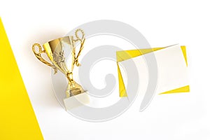 Champion trophy cup, envelope and blank sheet on white and yellow background. Top view. Flat lay. Sports. copy space