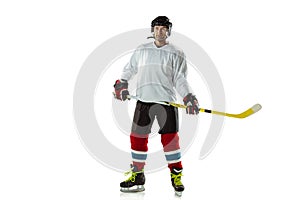 Young male hockey player with the stick on ice court and white background