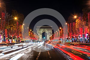 Champs Elysees avenue and the Arc de Triomphe decorated with red Christmas lights at night  in Paris France. Christmas holidays,