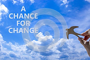 A chance for change symbol. Concept words A chance for change. Beautiful blue sky cloud background. Voter hand with wooden bird.