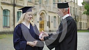 Chancellor of university giving diploma to student, shaking hand, commencement